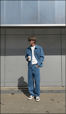 Model in blue denim standing against a dark gradient background